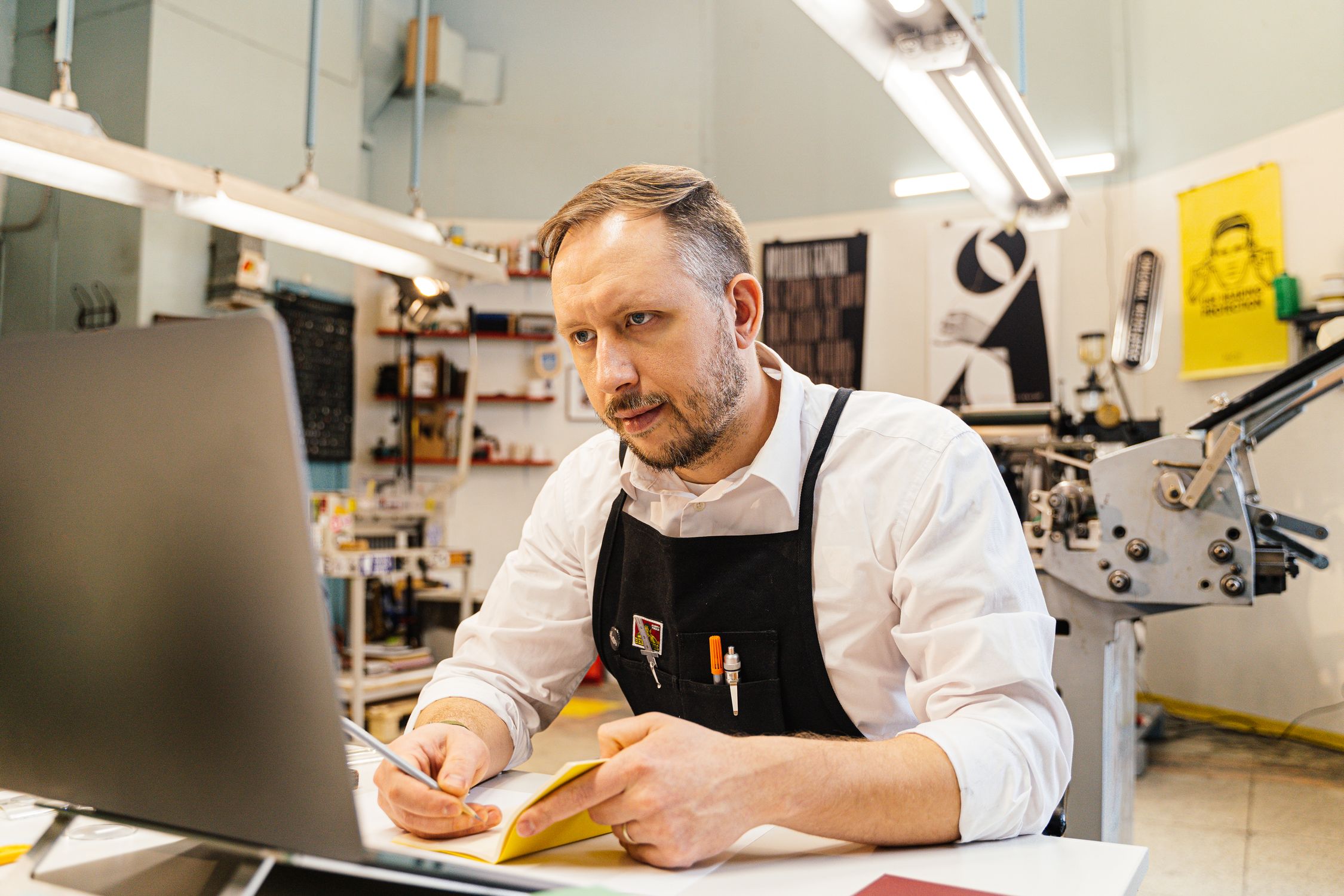 Small business owner working at computer in a busy print shop, managing their Google Business Profile