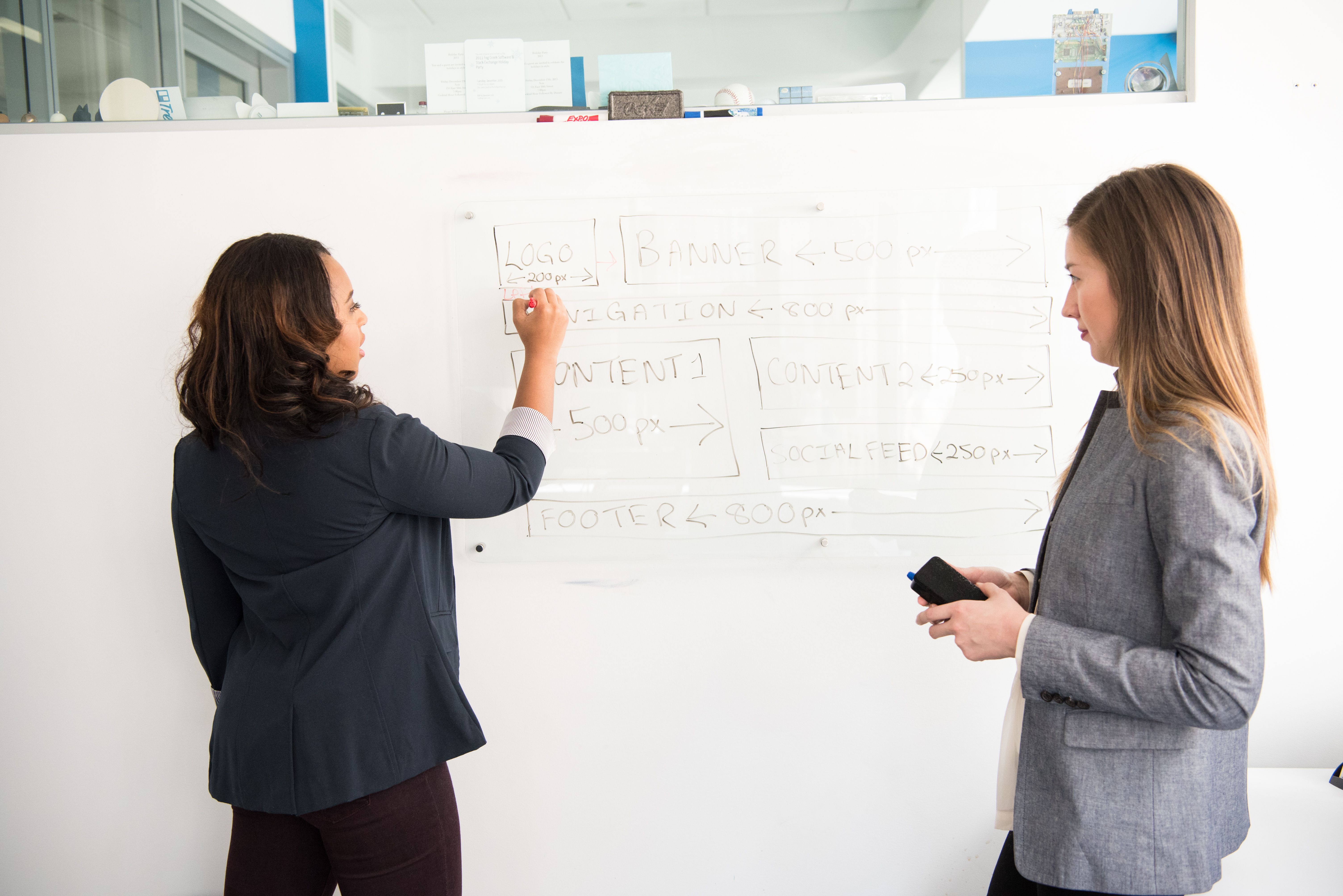 Two team members mapping out a content cluster strategy on a whiteboard with connected nodes