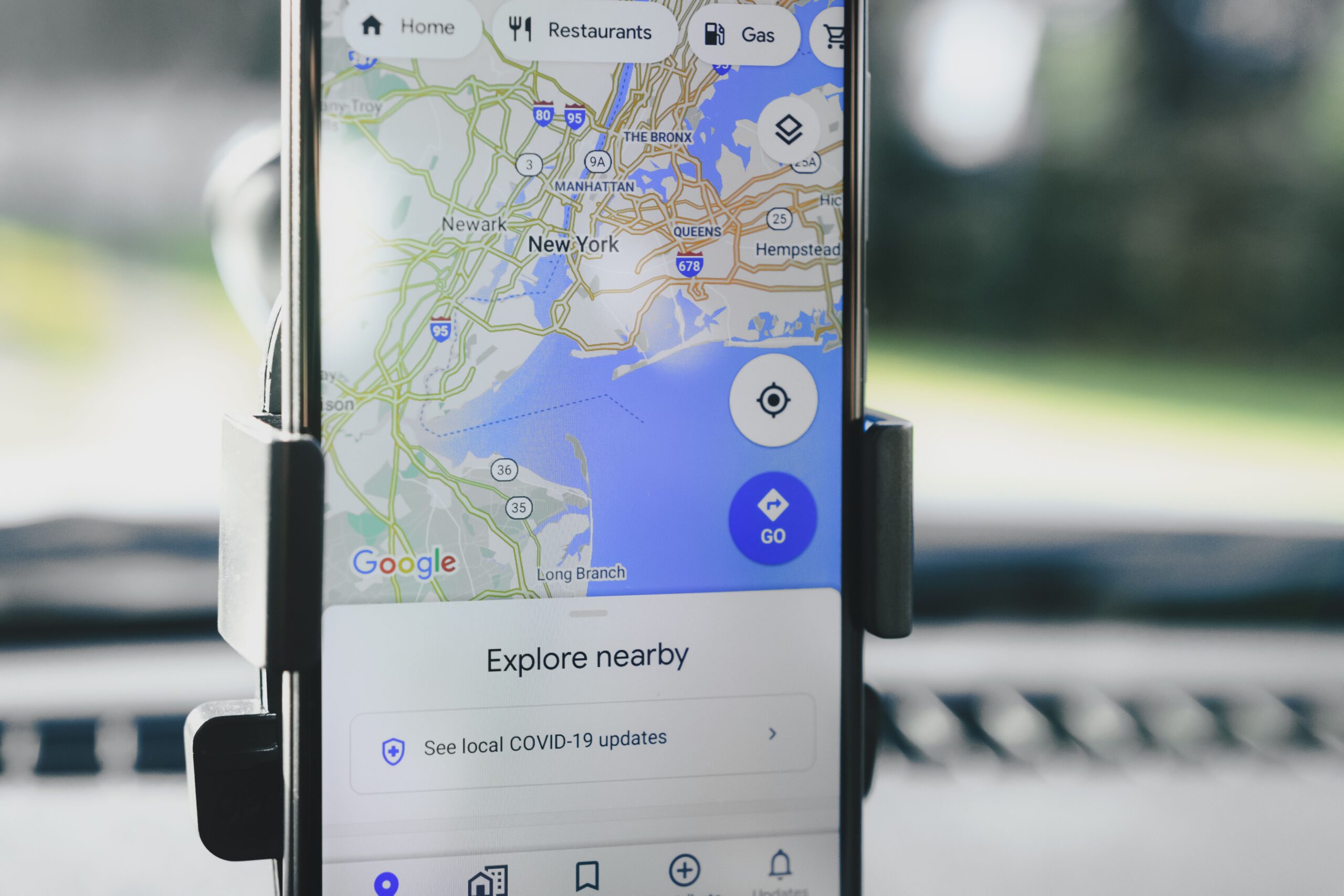 Person using Google Maps on a smartphone mounted in a car for local business search