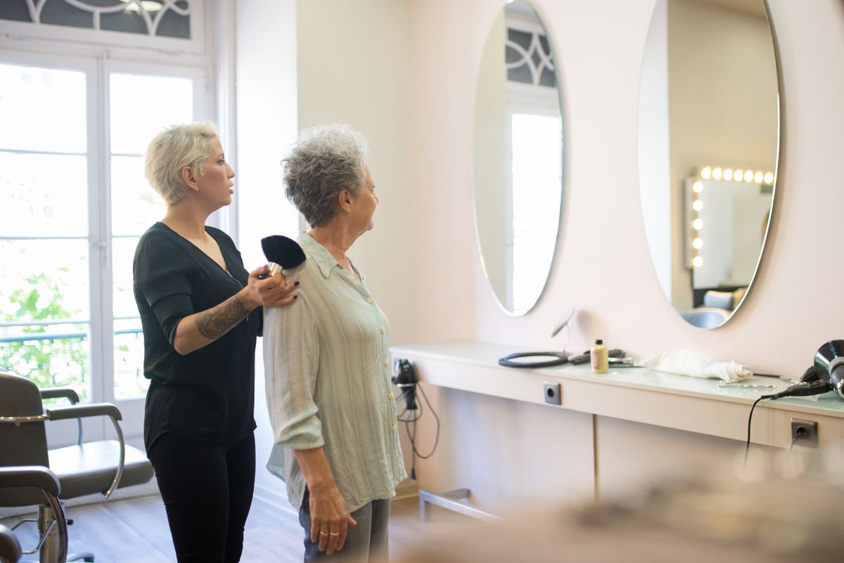 Hair stylist consulting with a client in front of salon mirrors during a service appointment