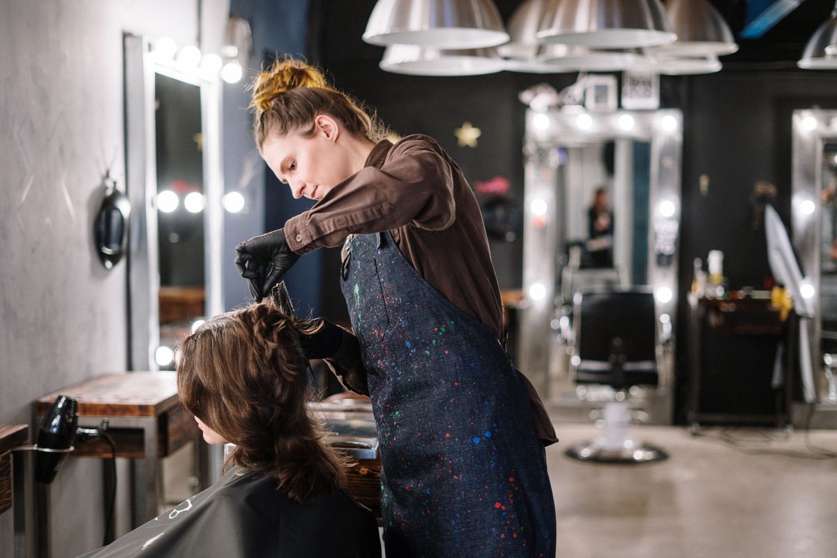 Professional hair stylist applying color treatment to a client in a stylish salon