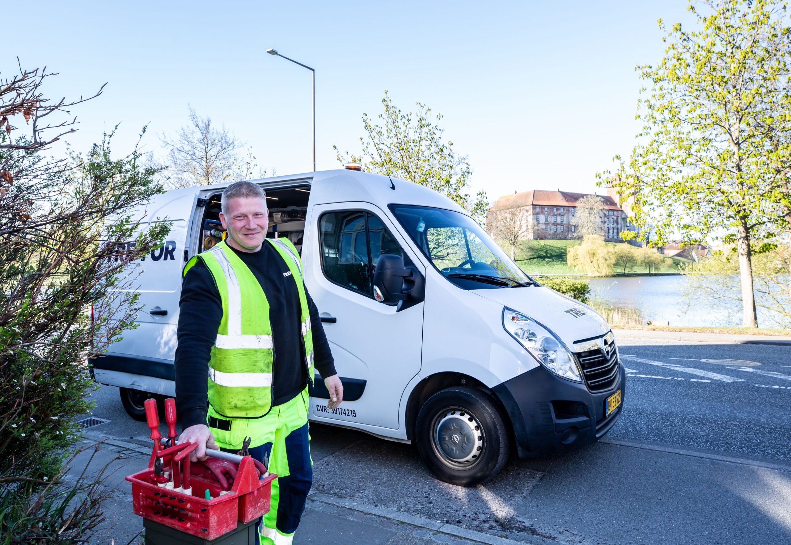 Local service worker in high-visibility vest standing beside a white work van