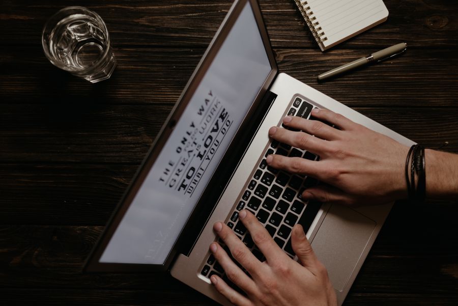 Hands typing on laptop keyboard working on SEO content formatted for featured snippet optimization