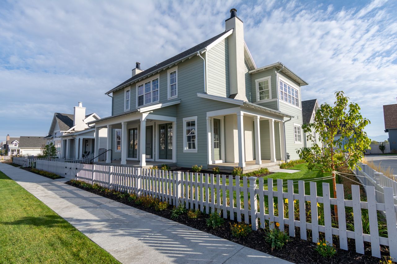 Charming suburban house with white picket fence under clear blue sky