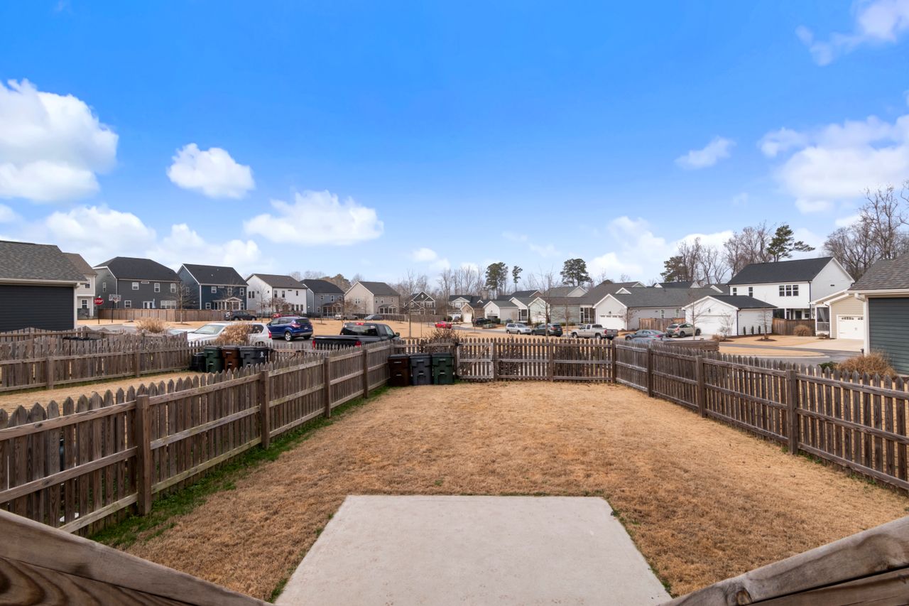 Suburban backyard with wooden fencing and modern homes in background