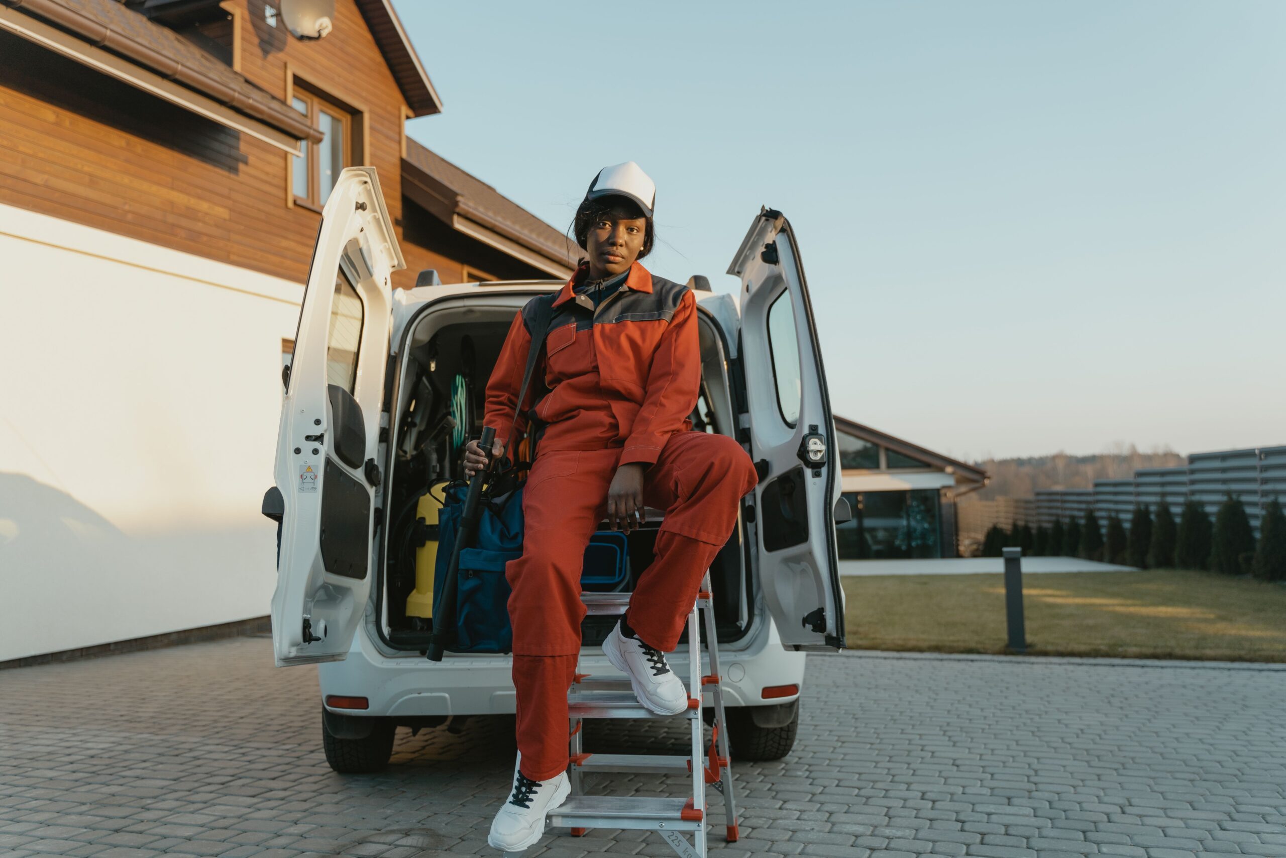 Service technician in orange uniform sitting in the back of a work van