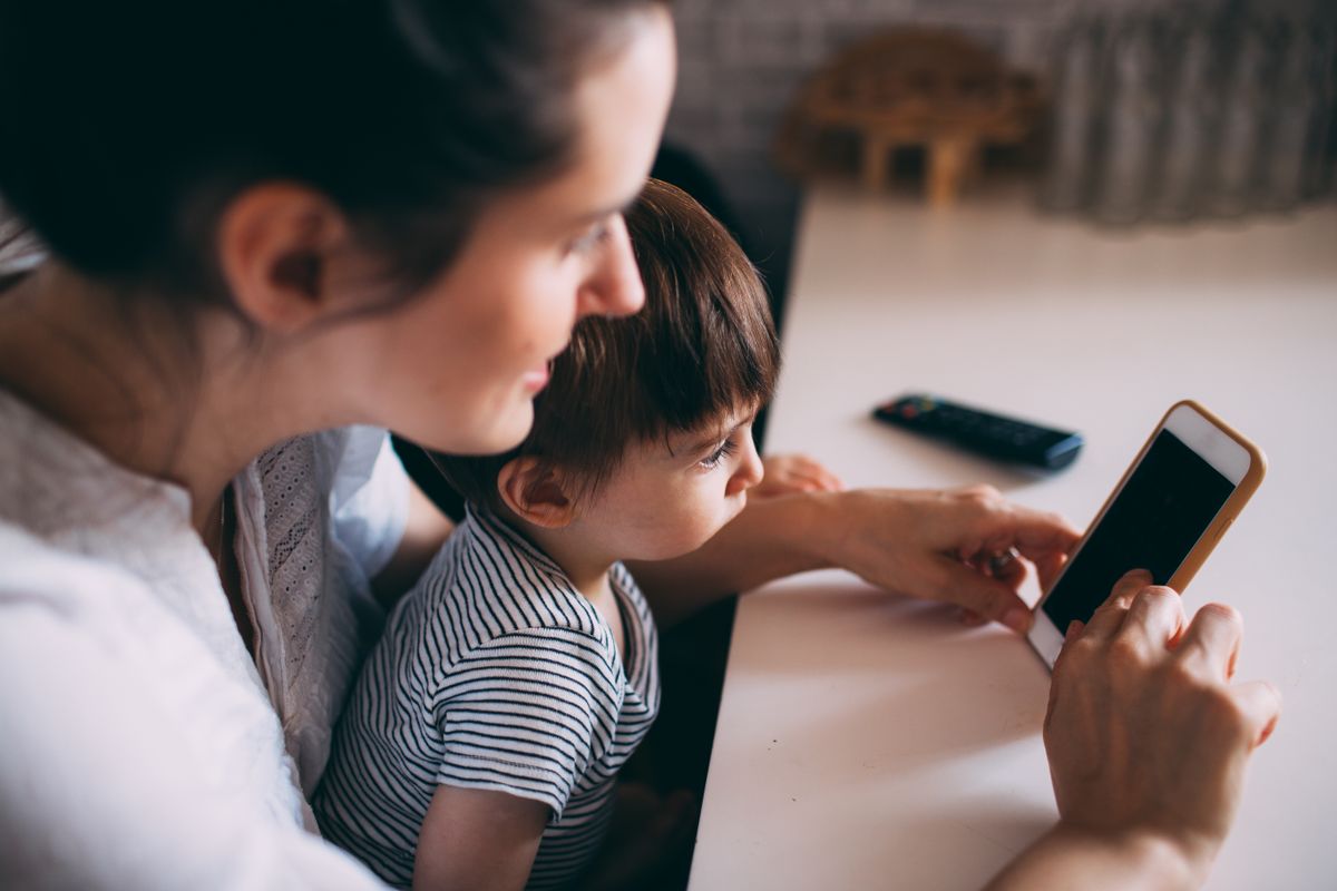Parent searching for daycare options on a smartphone while sitting with their child
