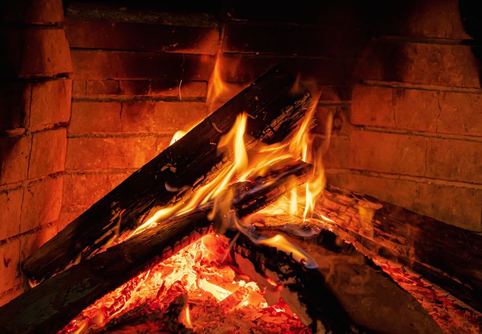 Wood burning inside a brick fireplace, the exact hazard behind most fall chimney inspection searches
