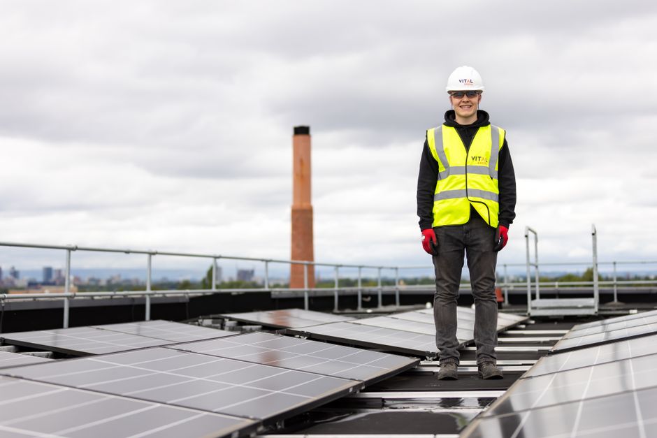 A technician standing on a residential rooftop near a brick chimney during an inspection