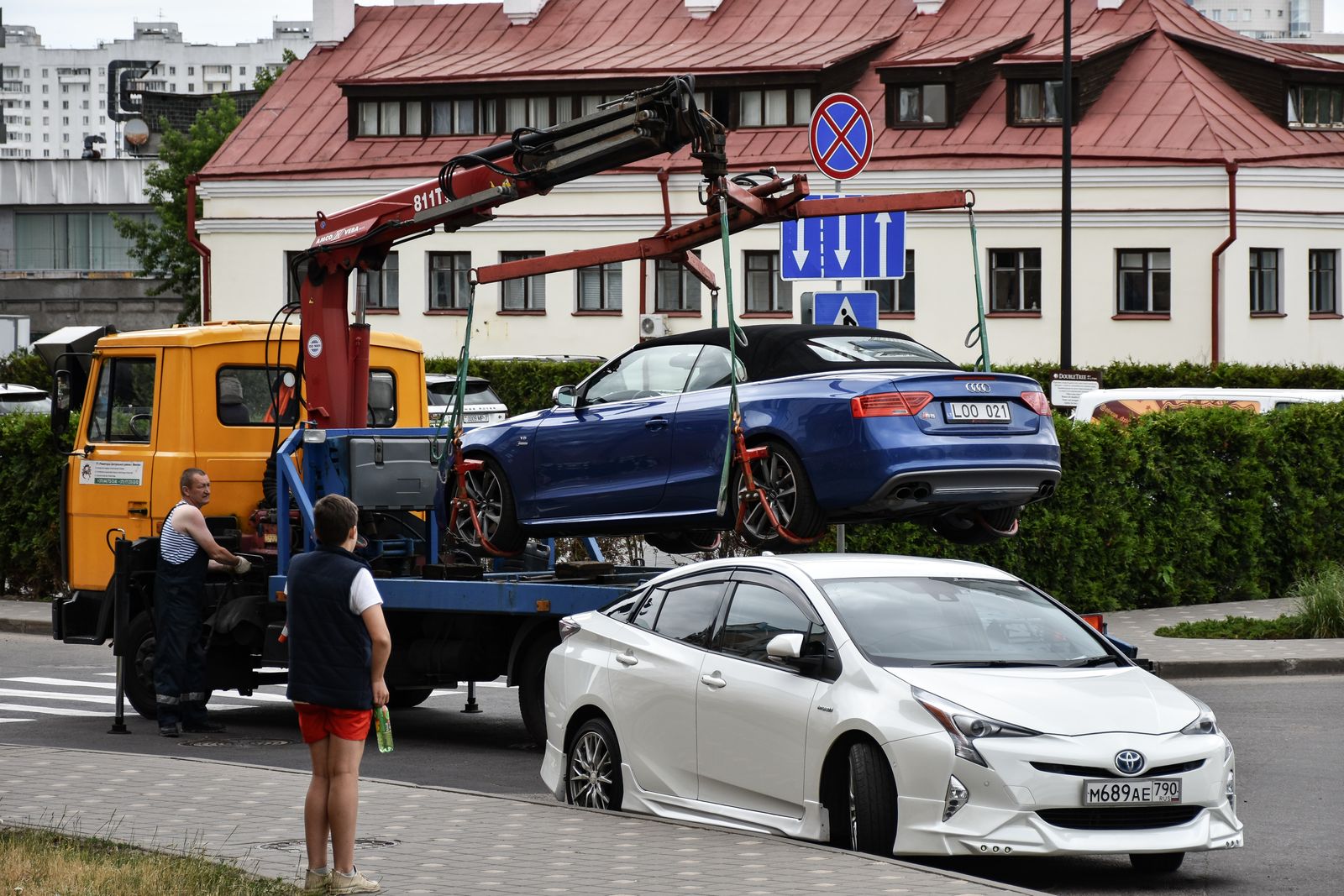 Tow truck towing a car through a busy city street