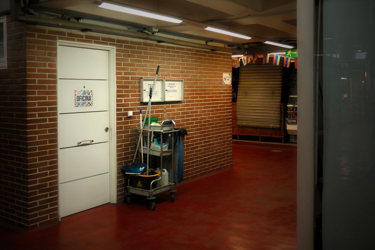 Commercial cleaning crew with supply cart in a brightly lit office hallway