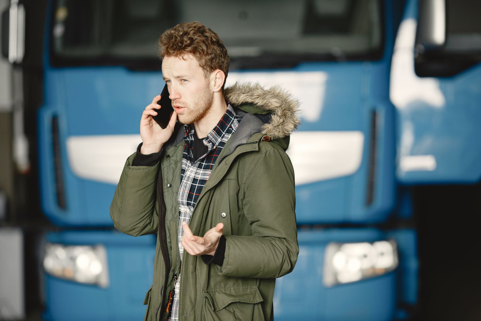 Tow truck driver taking a dispatch call in front of his truck