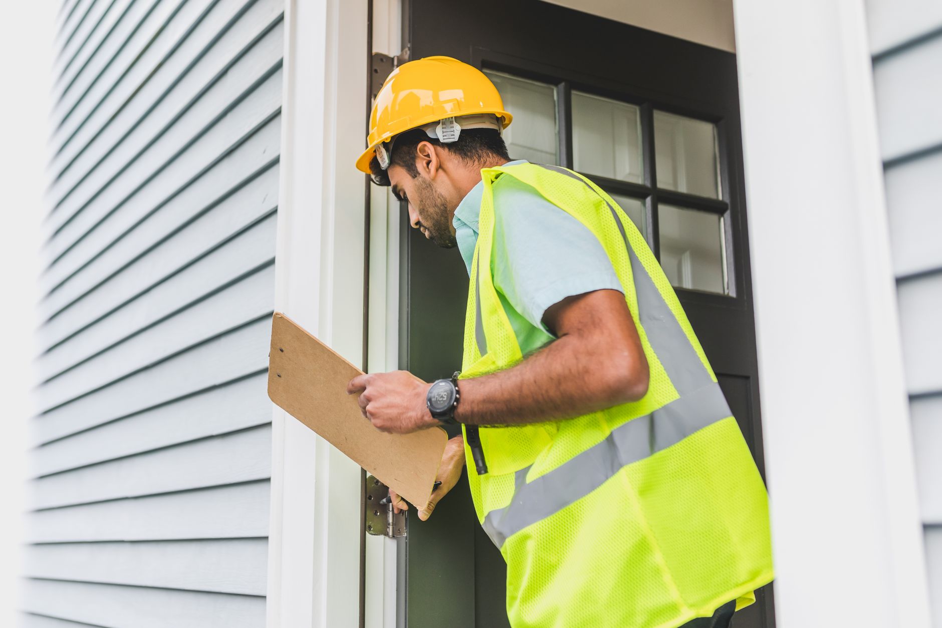 Contractor inspecting a home exterior with a clipboard before providing a gutter quote