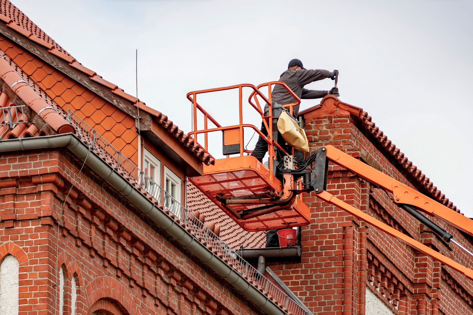Roofer working from a lift on a home exterior during gutter and roofline maintenance