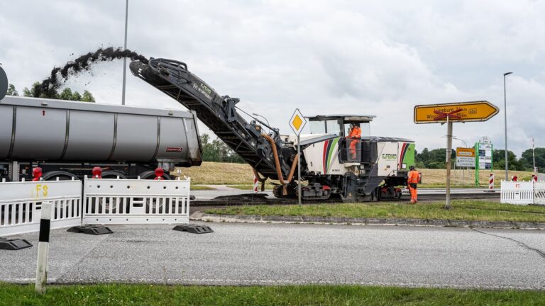 Asphalt paving contractor crew laying fresh asphalt on a road surface