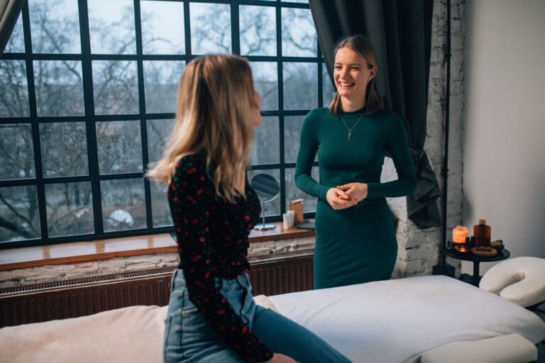 A massage therapist consulting with a client in a bright treatment room with a large window