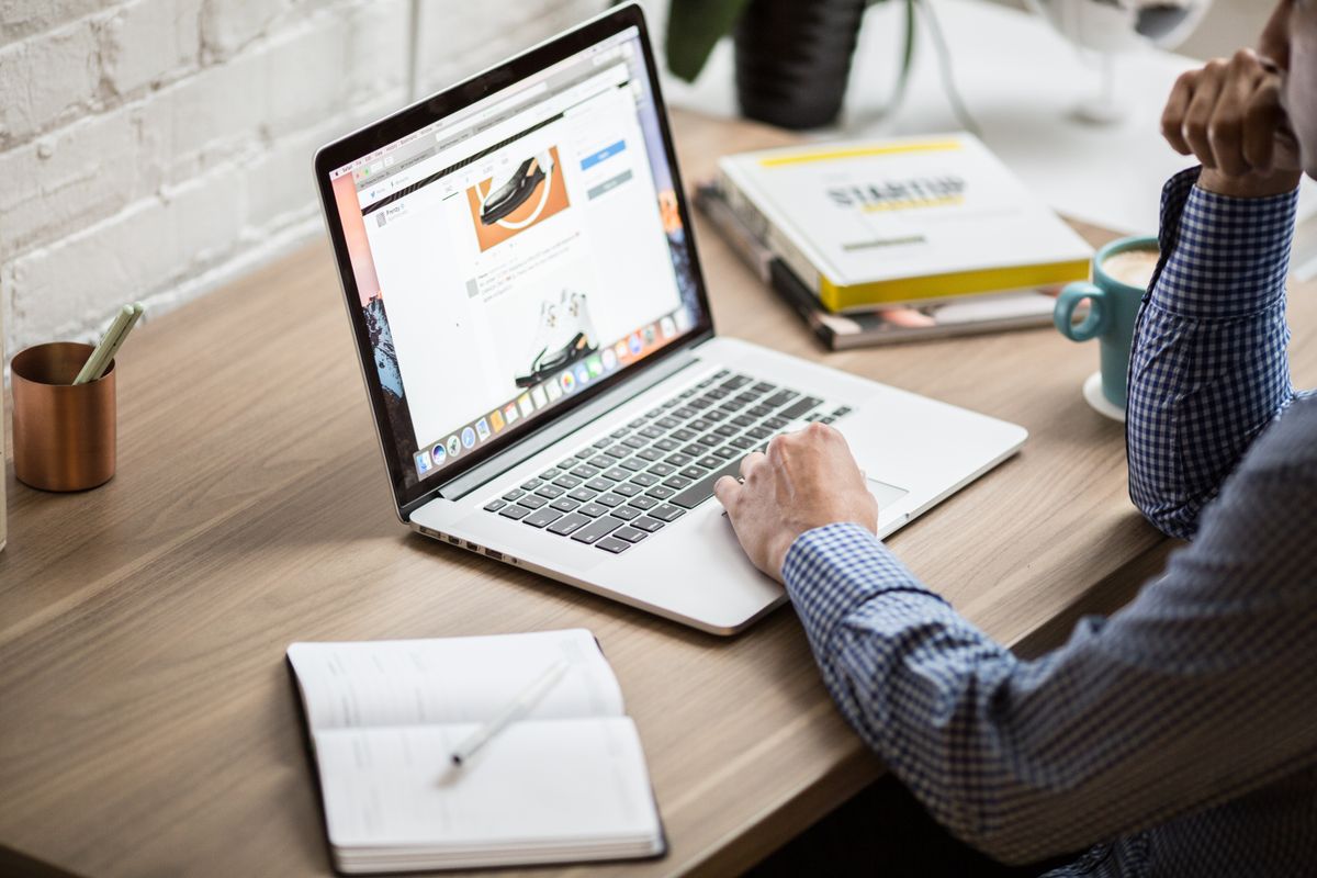 Entrepreneur writing a blog post on a laptop at a desk