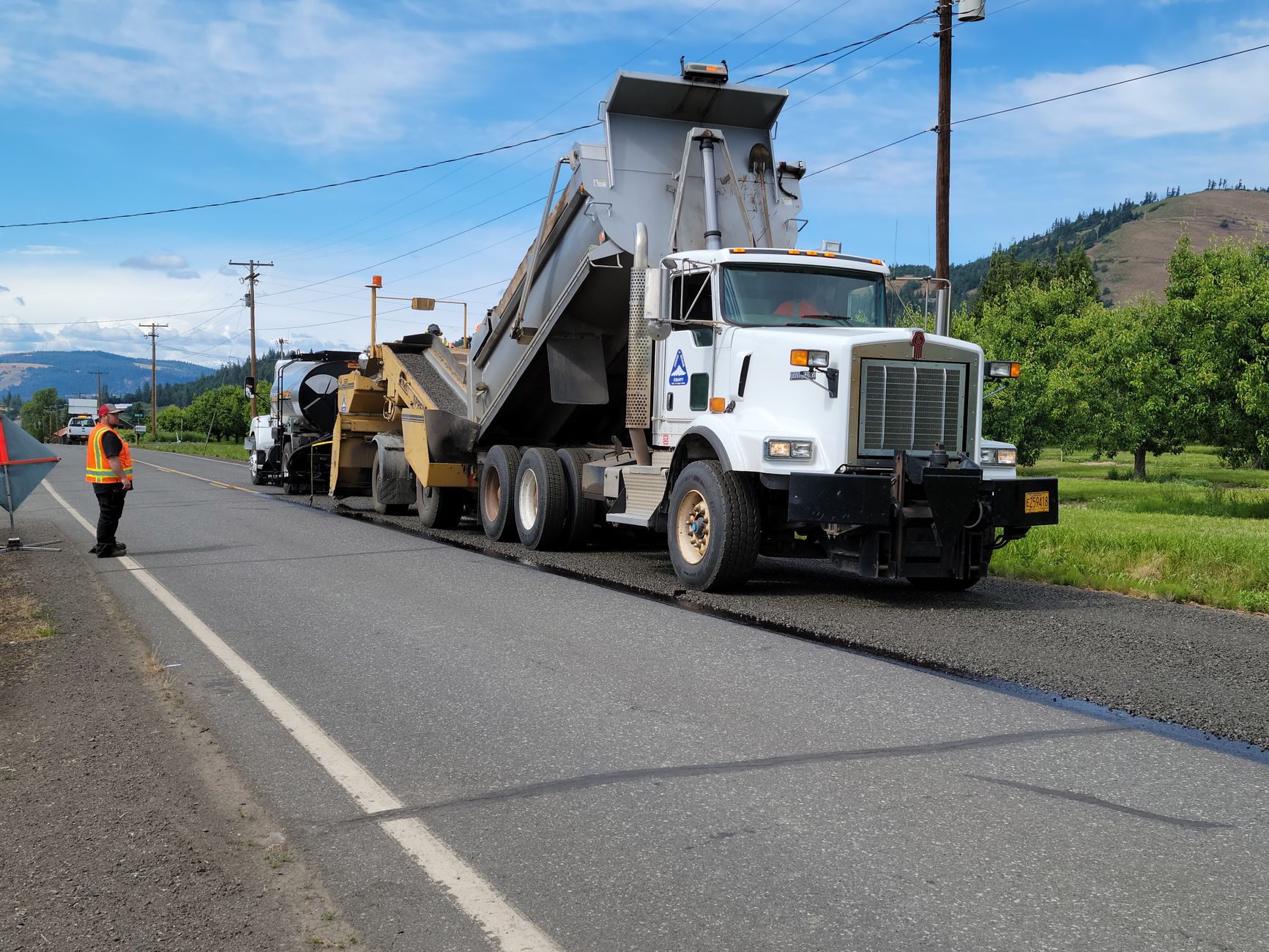 Asphalt paver and roller machinery compacting a new road surface