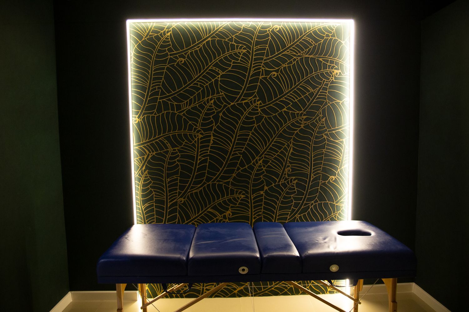 A softly lit massage room with a blue treatment table, the kind of space a well-optimized Google Business Profile and website need to represent accurately