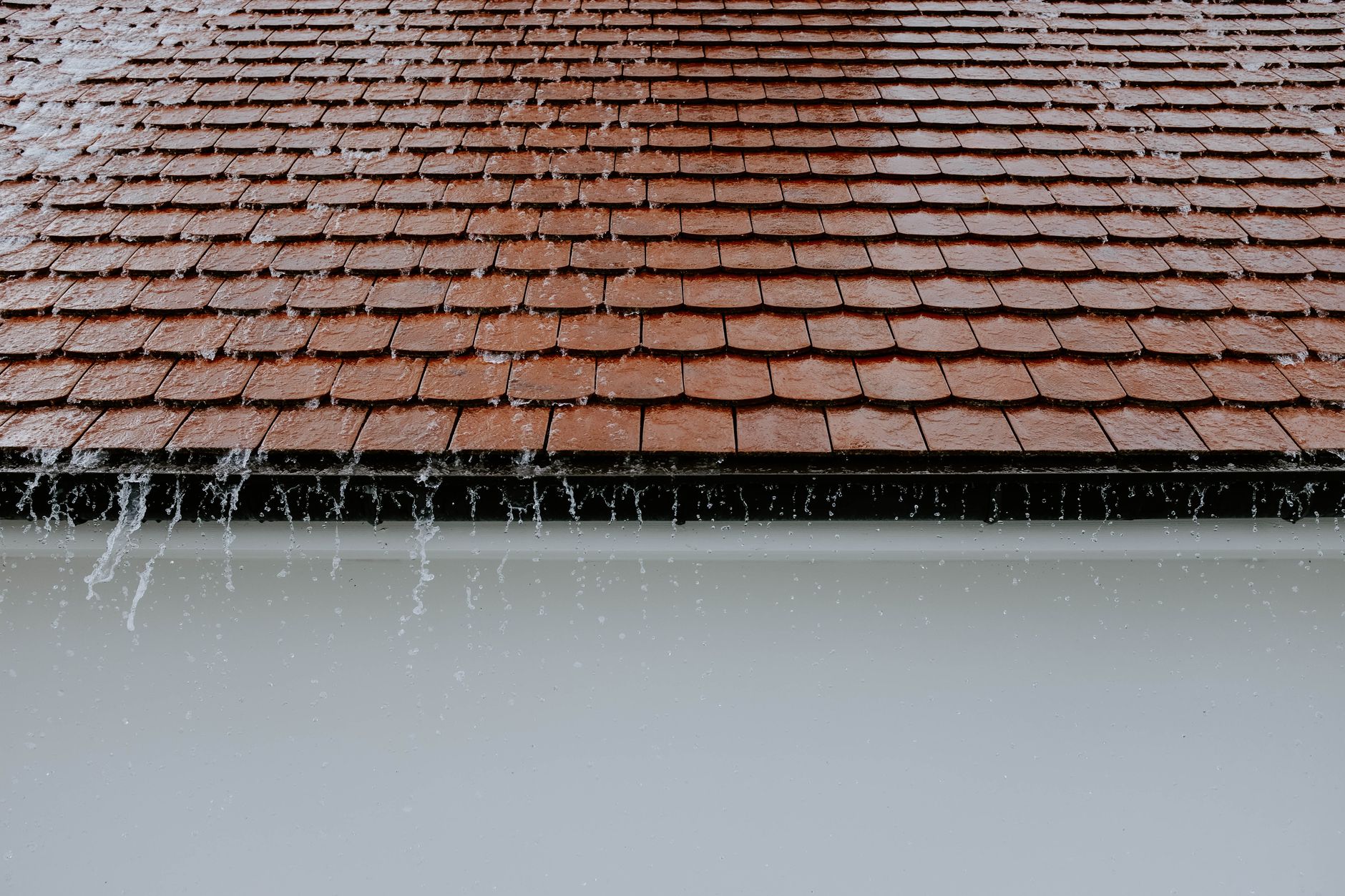 Rainwater overflowing off a roof edge without functioning gutters