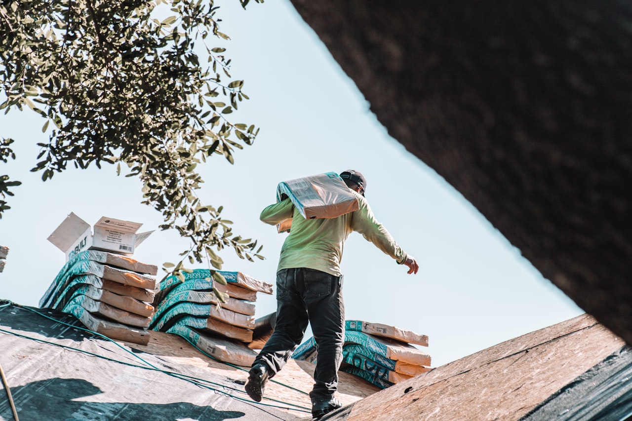 roofer carrying bundle of shingles on residential roof
