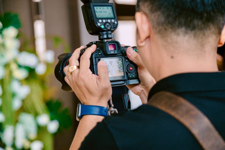 Close-up of a photographer using a camera with flash indoors, focusing on a screen view.