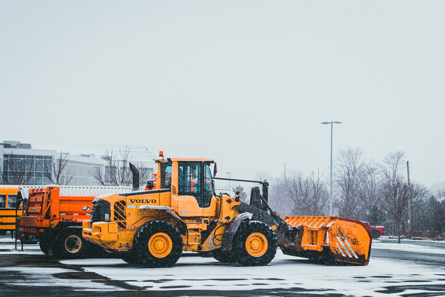 Commercial parking lot being cleared by a snow plow truck