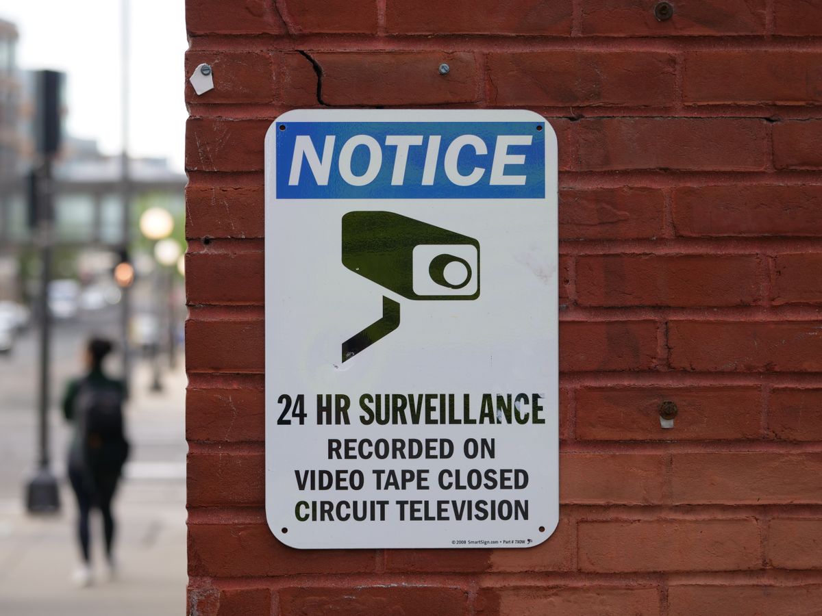 Surveillance notice sign posted on a brick wall in an urban setting