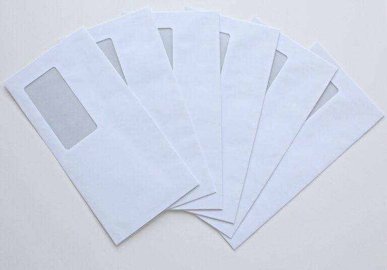 A set of white window envelopes fanned out on a flat surface, ready for mailing or office use.