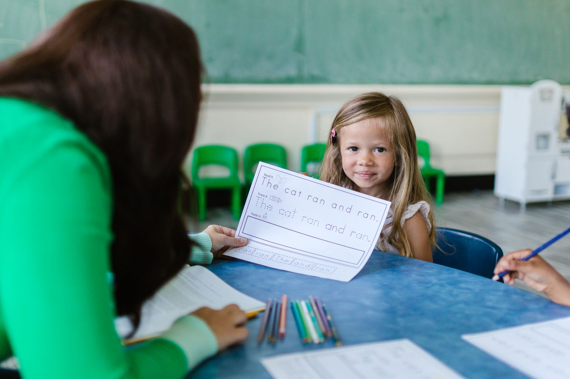 Young girl in a classroom working alongside her teacher