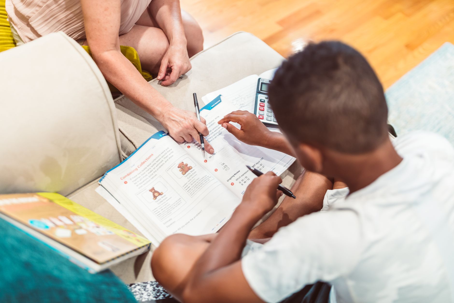 Person helping a young boy with his homework at a desk