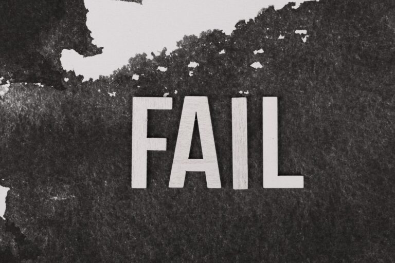 Grayscale image of the word 'FAIL' on a textured, monochrome background.