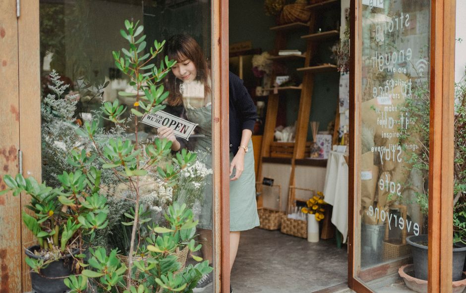 Shop owner flipping her storefront sign to Open at a boutique flower shop