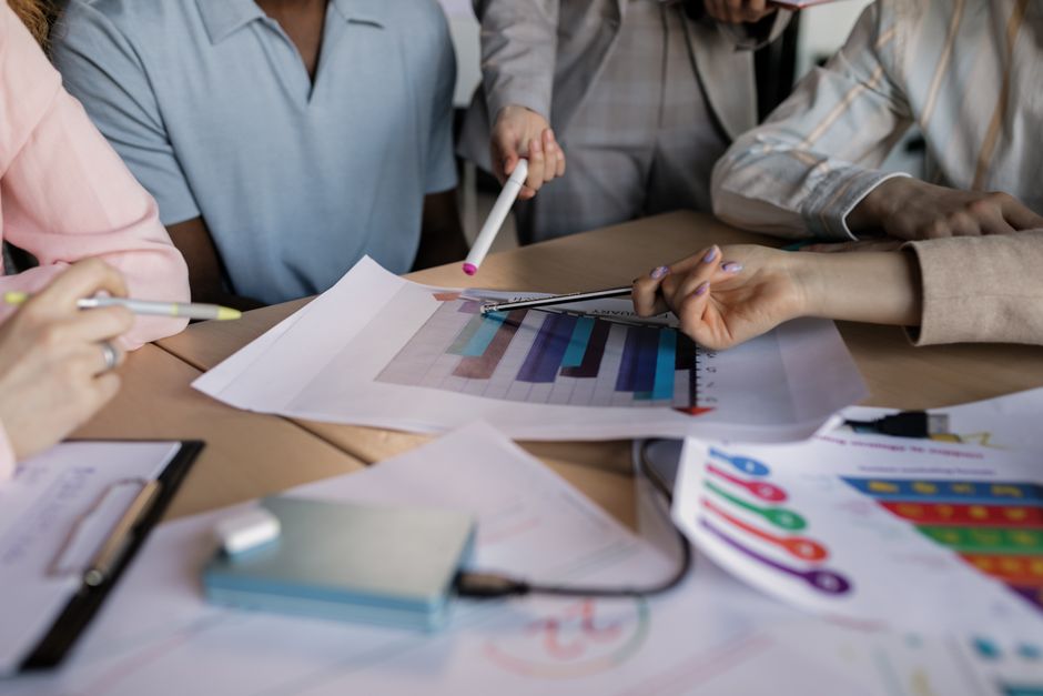 Small business team reviewing marketing performance charts and reports on paper