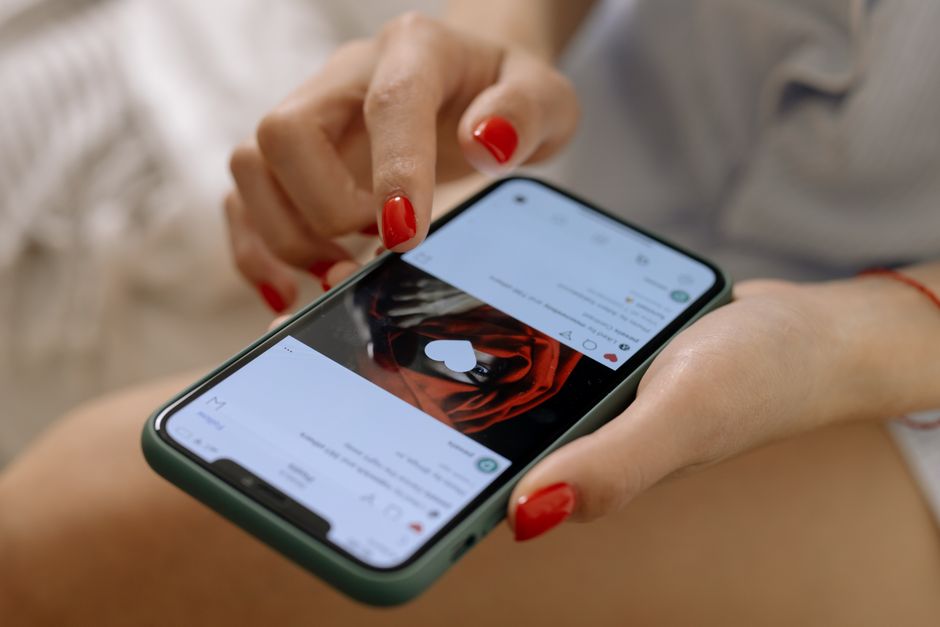 Woman scrolling and liking posts in an Instagram feed on her phone