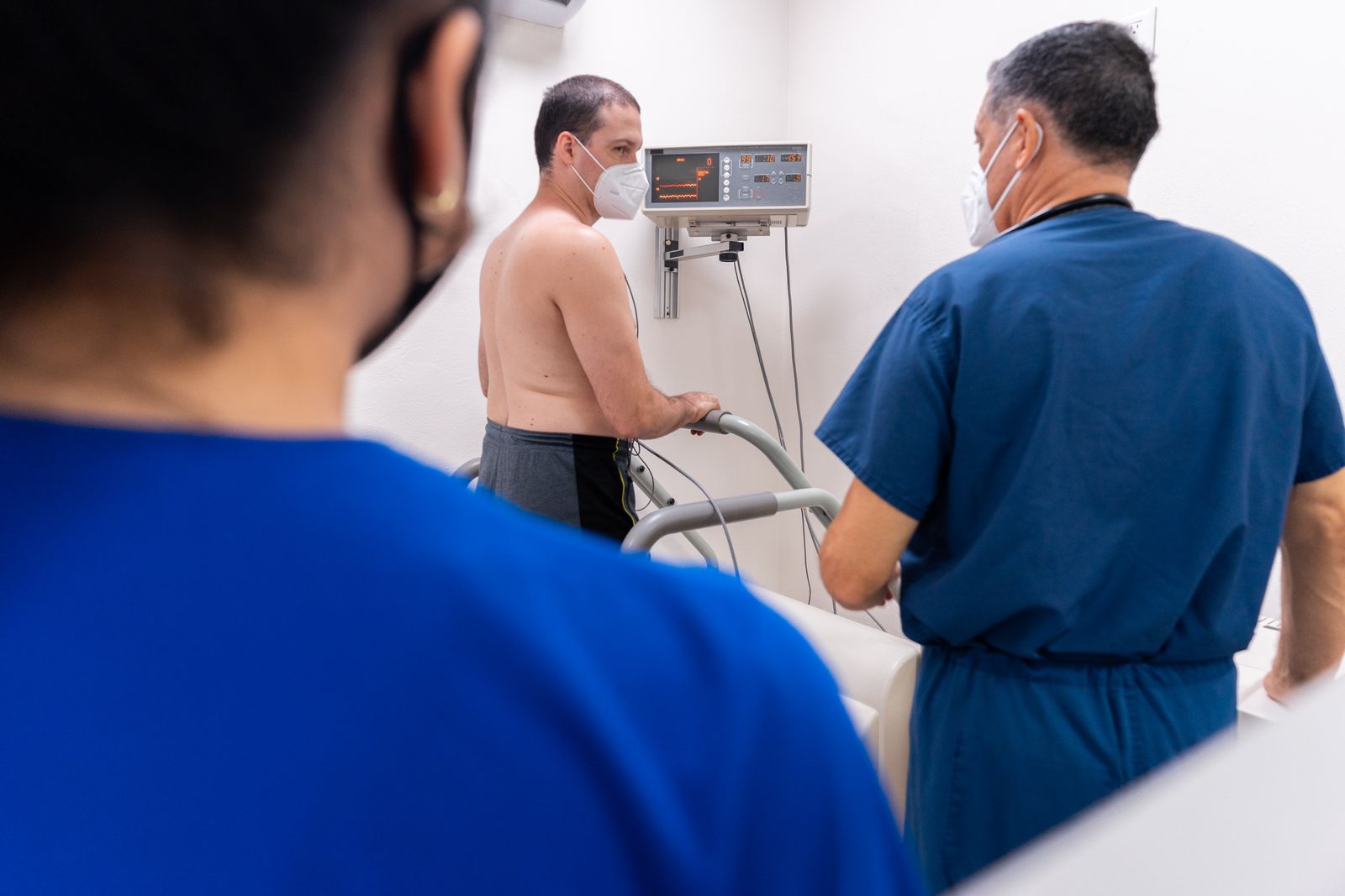 Cardiology care team monitoring a patient walking on a treadmill during a cardiac stress test