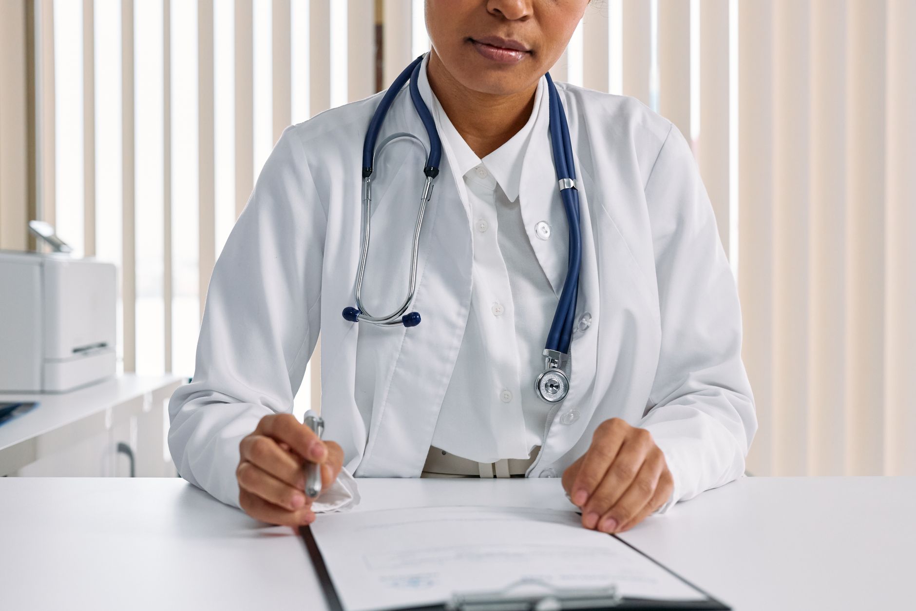 Physician reviewing paperwork and insurance forms at a clinic desk