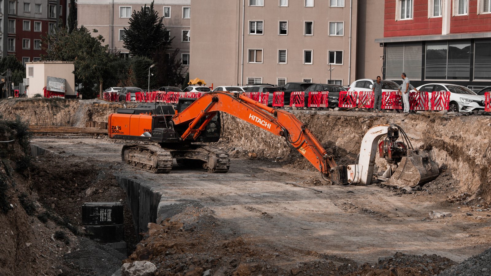 Excavator working a tight urban excavation site surrounded by apartment buildings