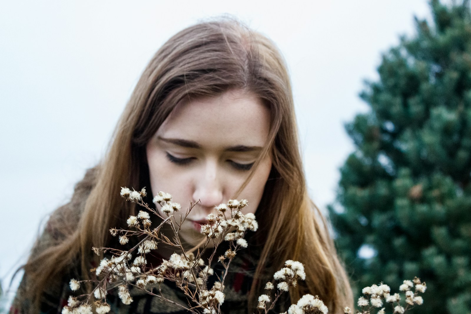 Woman outdoors examining seasonal flowering plants that trigger pollen allergies