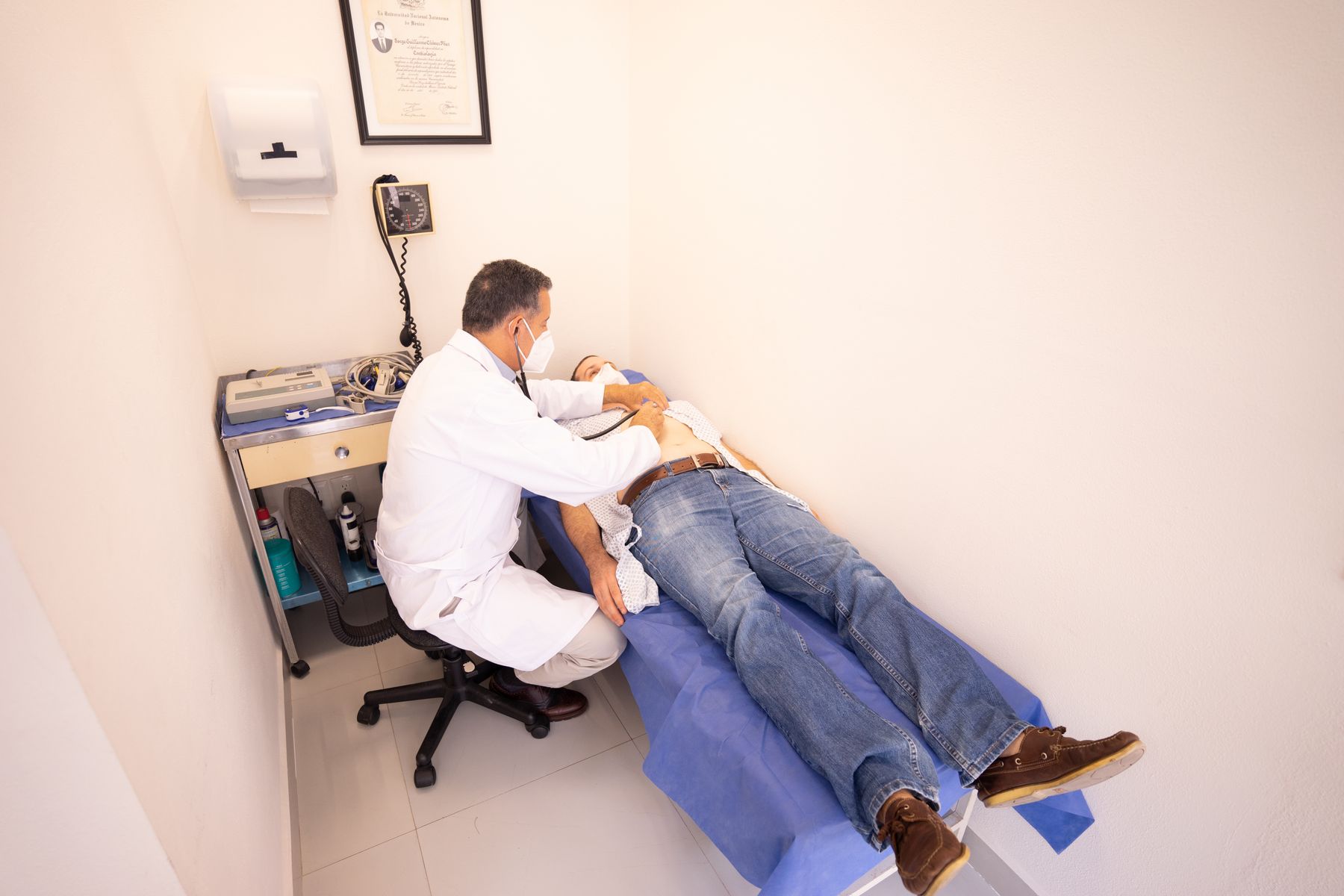 Doctor examining a patient with a stethoscope in a GI practice exam room