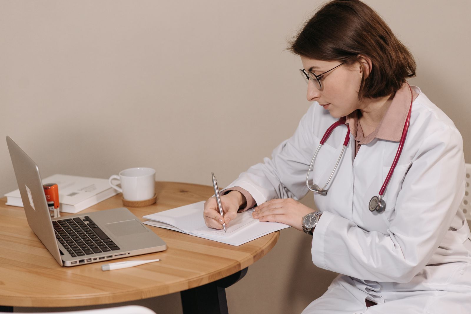 Physician writing patient notes at a desk