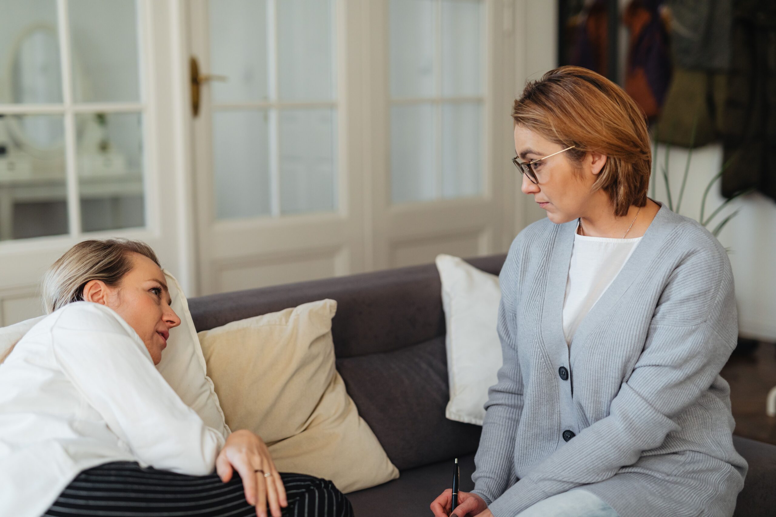A therapist listens attentively during a counseling session in a cozy indoor setting
