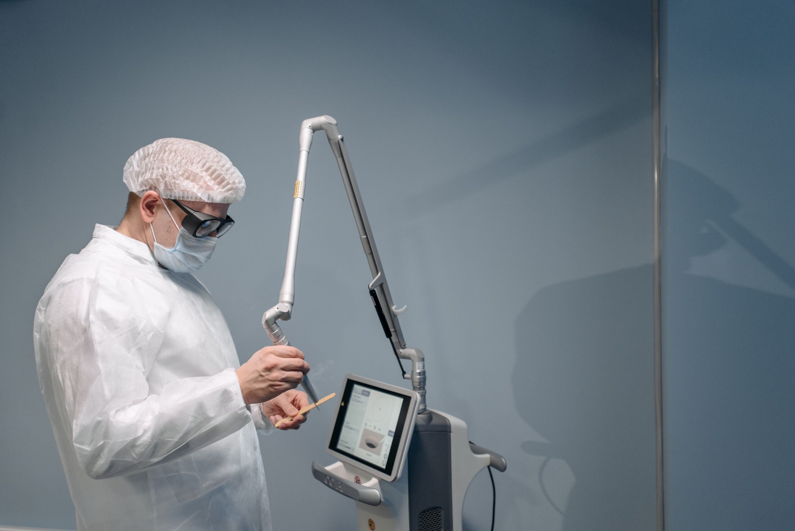 Doctor in protective eyewear operating laser equipment during a vision correction procedure
