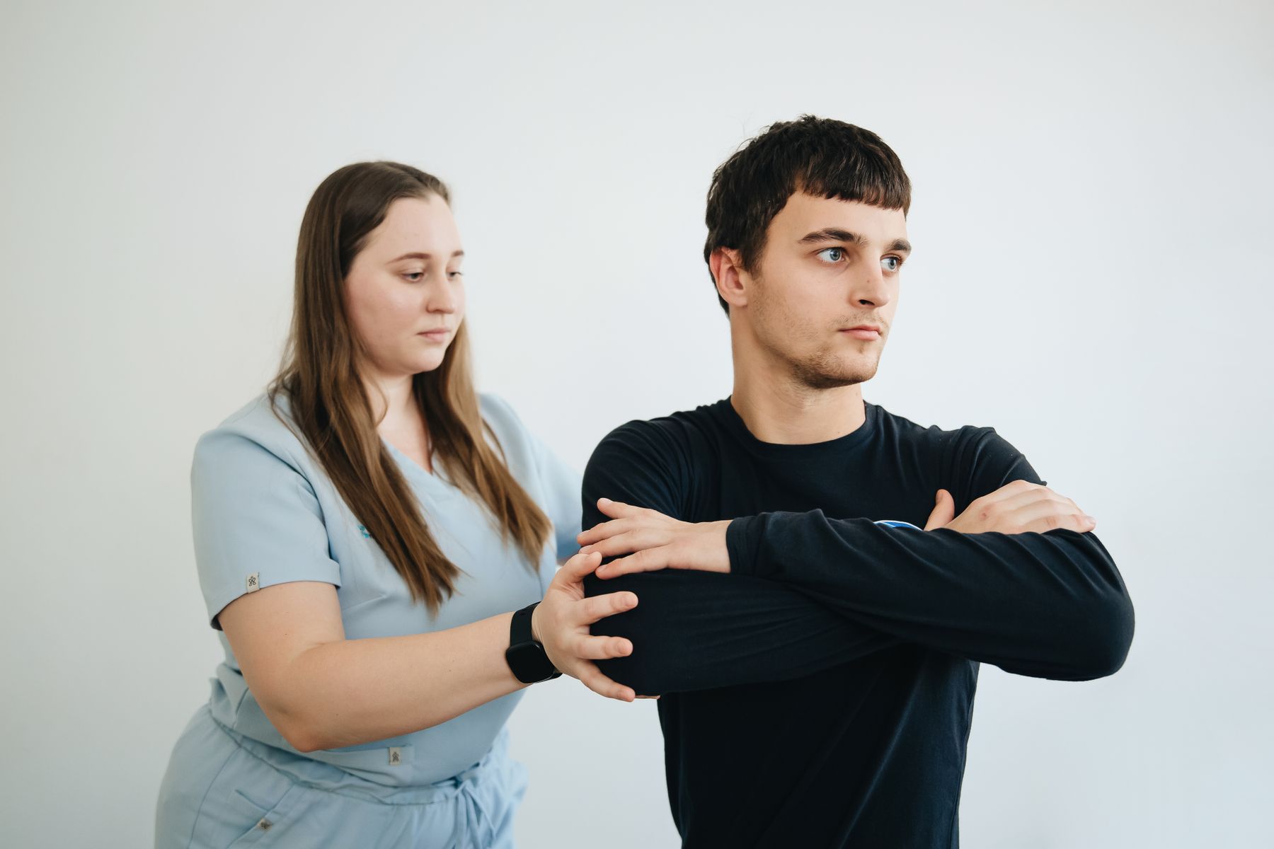 A physical therapist assisting a patient through arm rehabilitation exercises in a clinic
