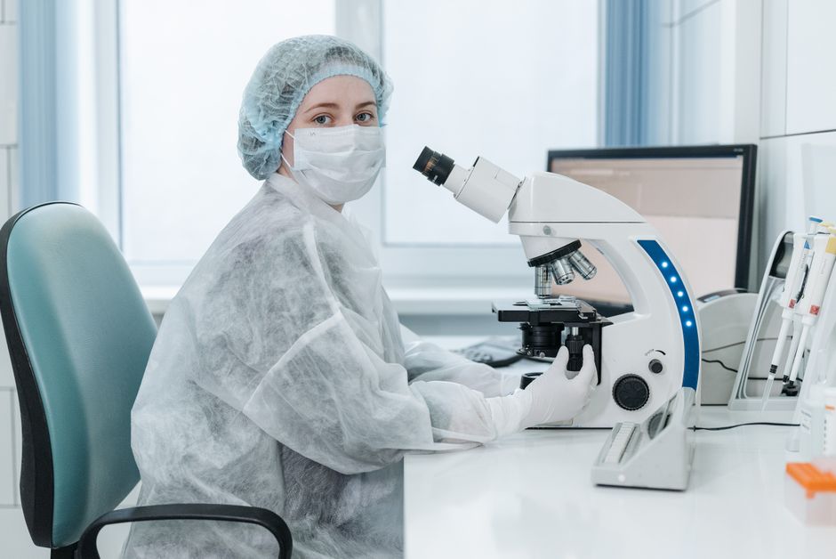 Lab technician examining samples under a microscope in a fertility clinic embryology lab