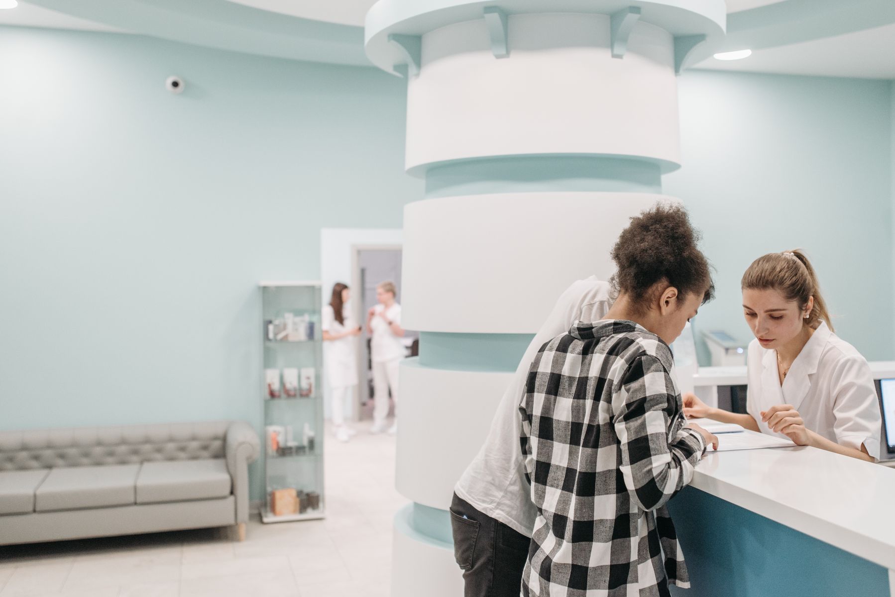 Healthcare staff assisting patients at a modern clinic reception desk