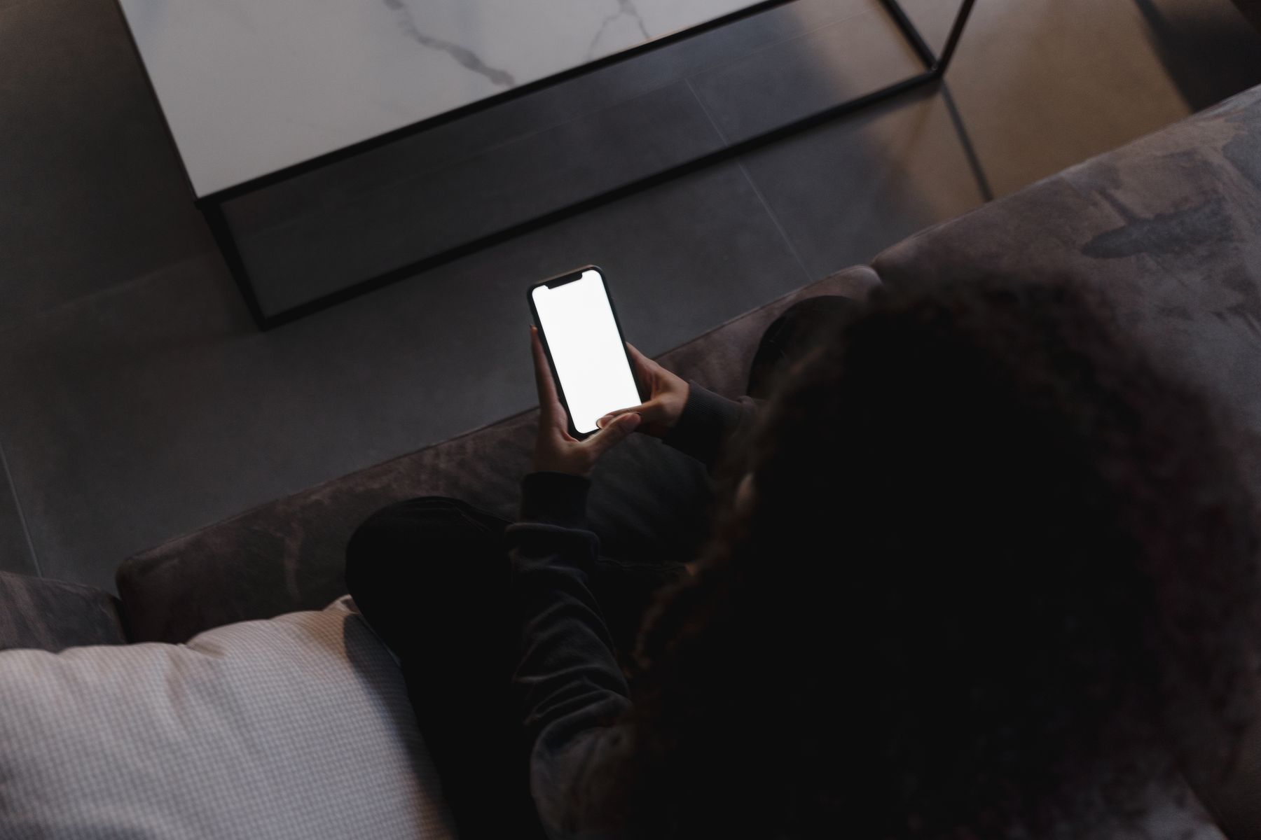 Person scrolling a real estate listings app on a smartphone, similar to browsing Zillow Premier Agent listings