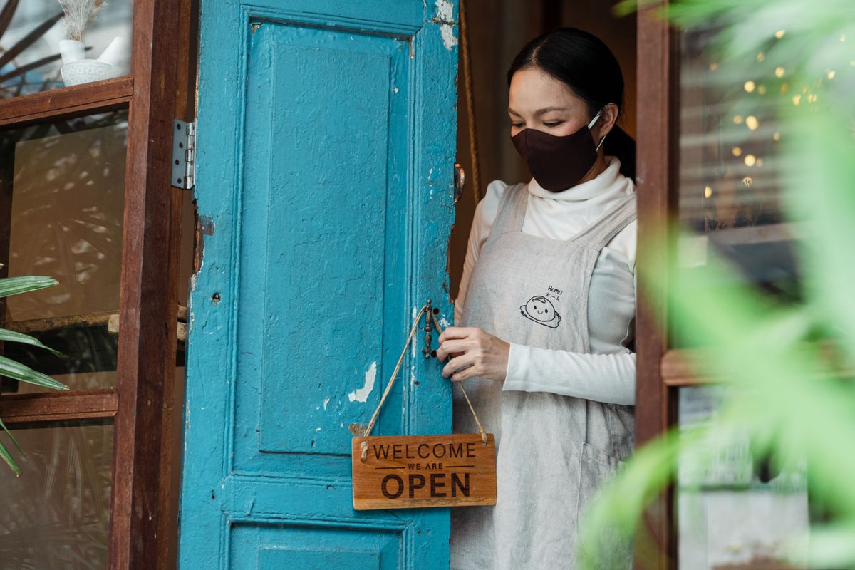 Shop owner hanging a welcome sign on the door of her storefront