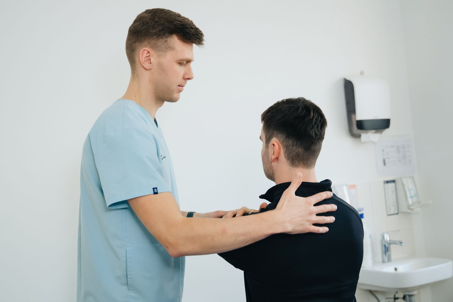 A physiotherapist working with a patient on shoulder mobility in a clinical setting