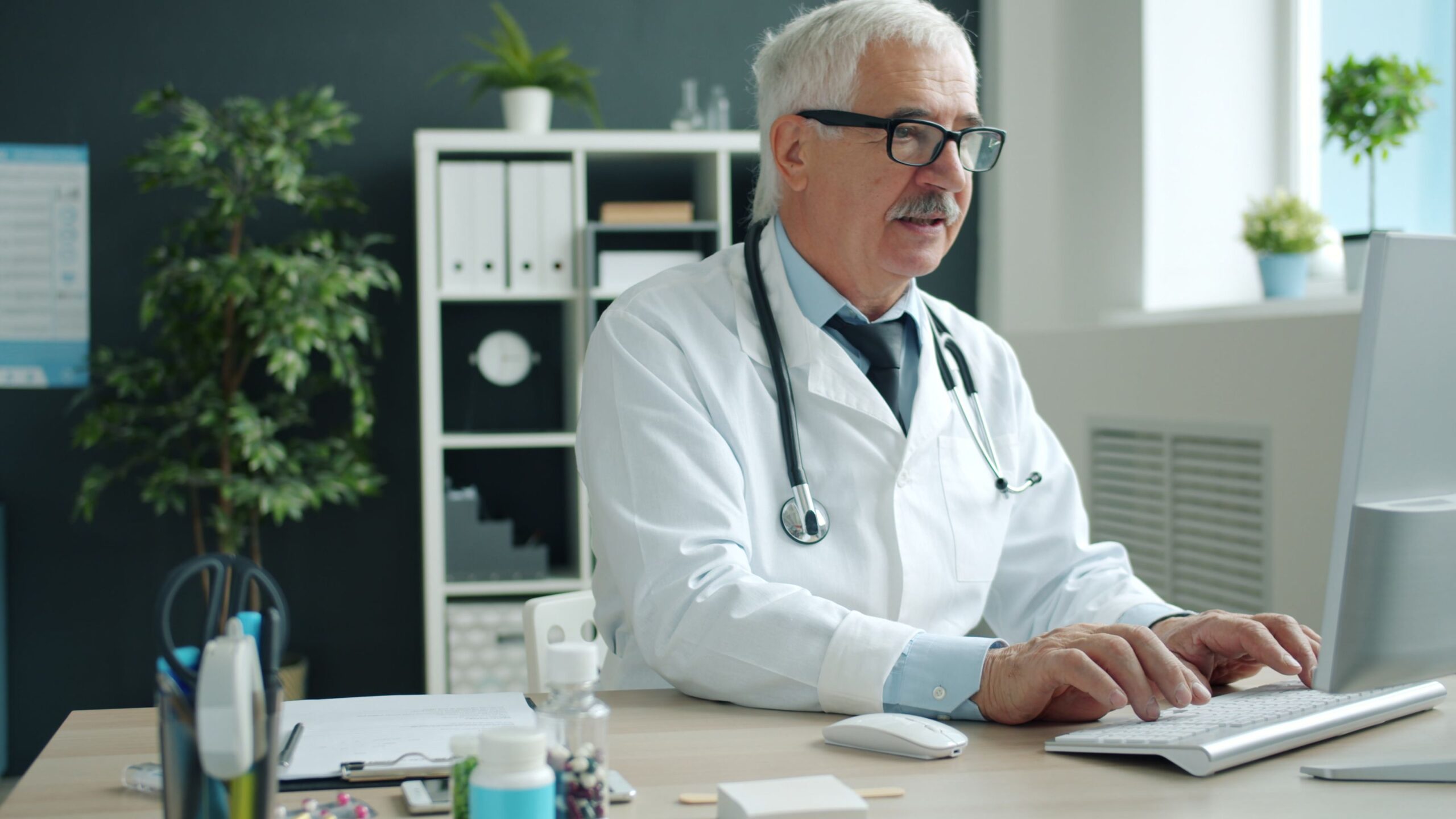 Doctor typing on a computer keyboard at a desk in a medical office